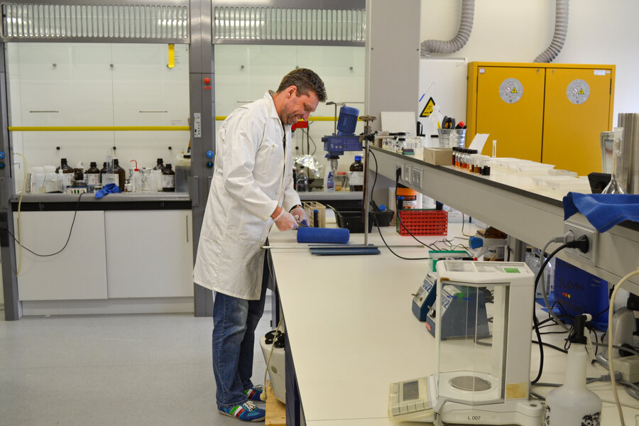 Laboratoriummedewerker bereidt een proef voor aan een werkbank in een chemisch laboratorium.